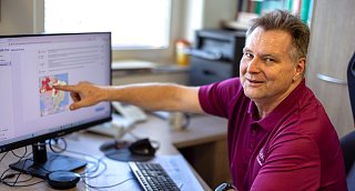 Arzt deutet auf Landkarte am PC